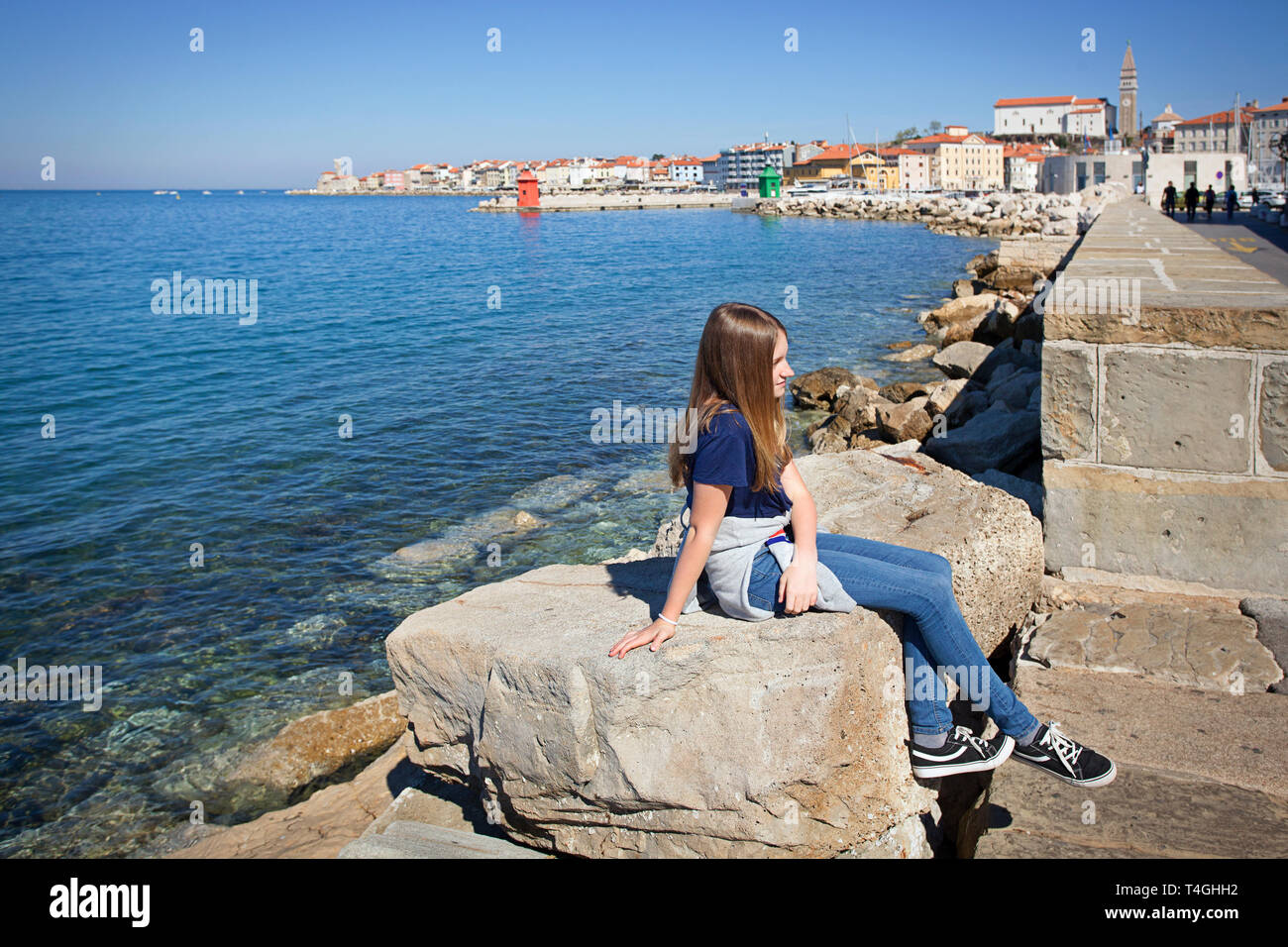 Junges Mädchen sitzen auf den Felsen am Meer Stockfoto