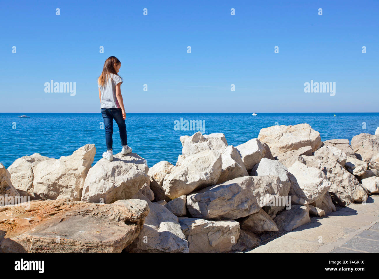 Junge Mädchen auf Felsen von Waters Edge, Adria Stockfoto