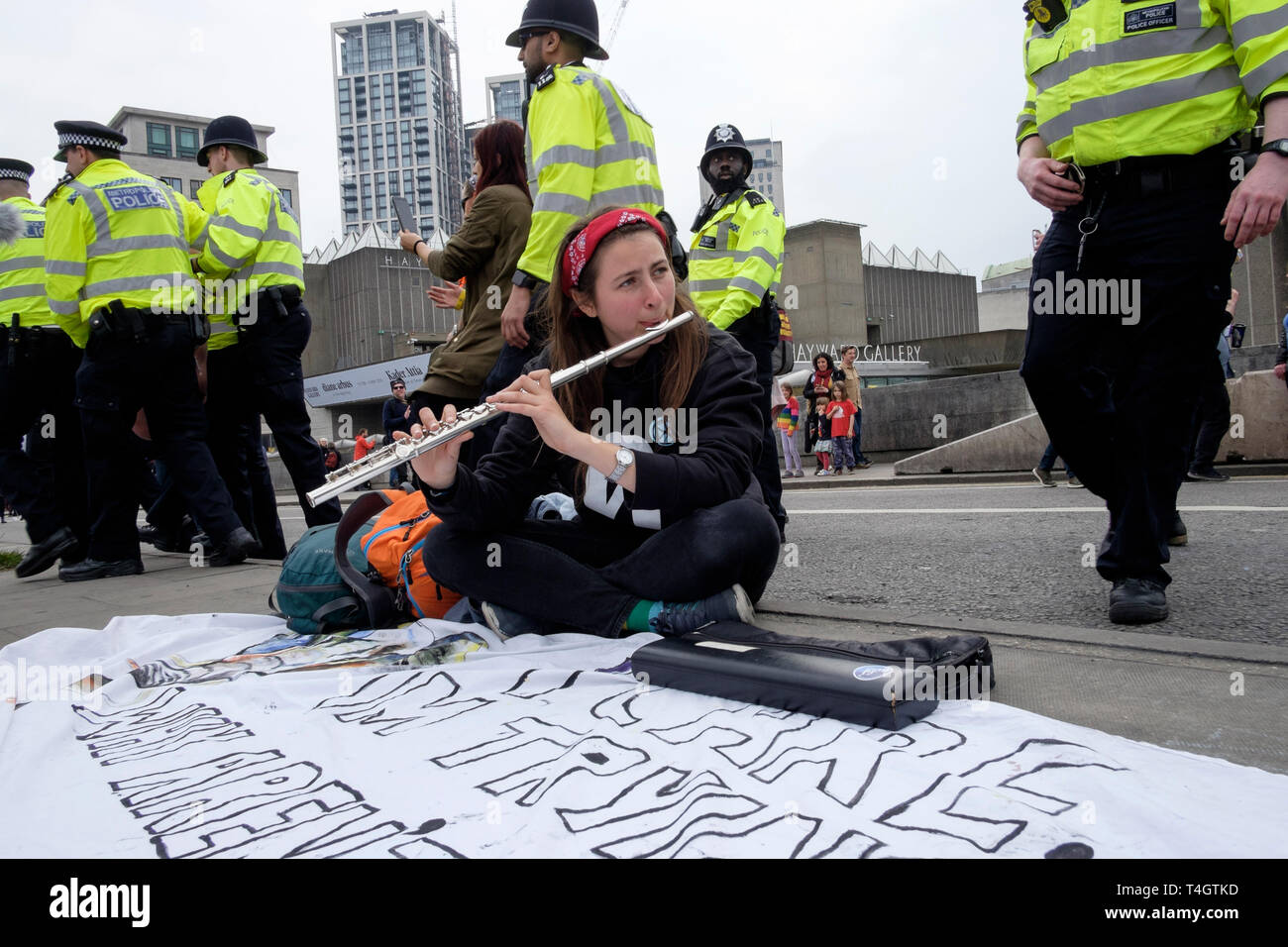 Extinction Rebellion Aktivisten Occupy Waterloo Bridge, London, April 2019: Ein junger Flötist spielt als Polizei gegen Demonstranten vorgeht. Stockfoto