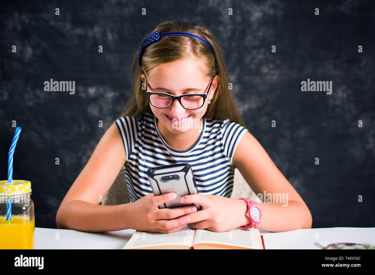 Gerne jugendlich Mädchen suchen auf Ihr Telefon und lächelnd Stockfoto