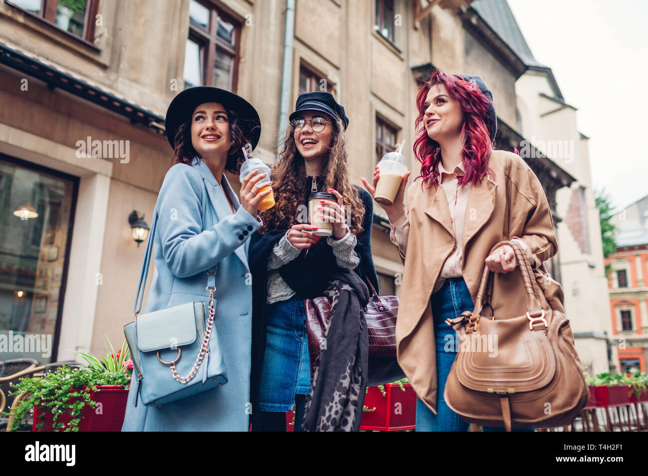 Drei weibliche Freunde Drinks im Freien. Gerne Frauen klirren Kaffee, Orangensaft und Kaffee Tassen und lachend durch Cafe Stockfoto