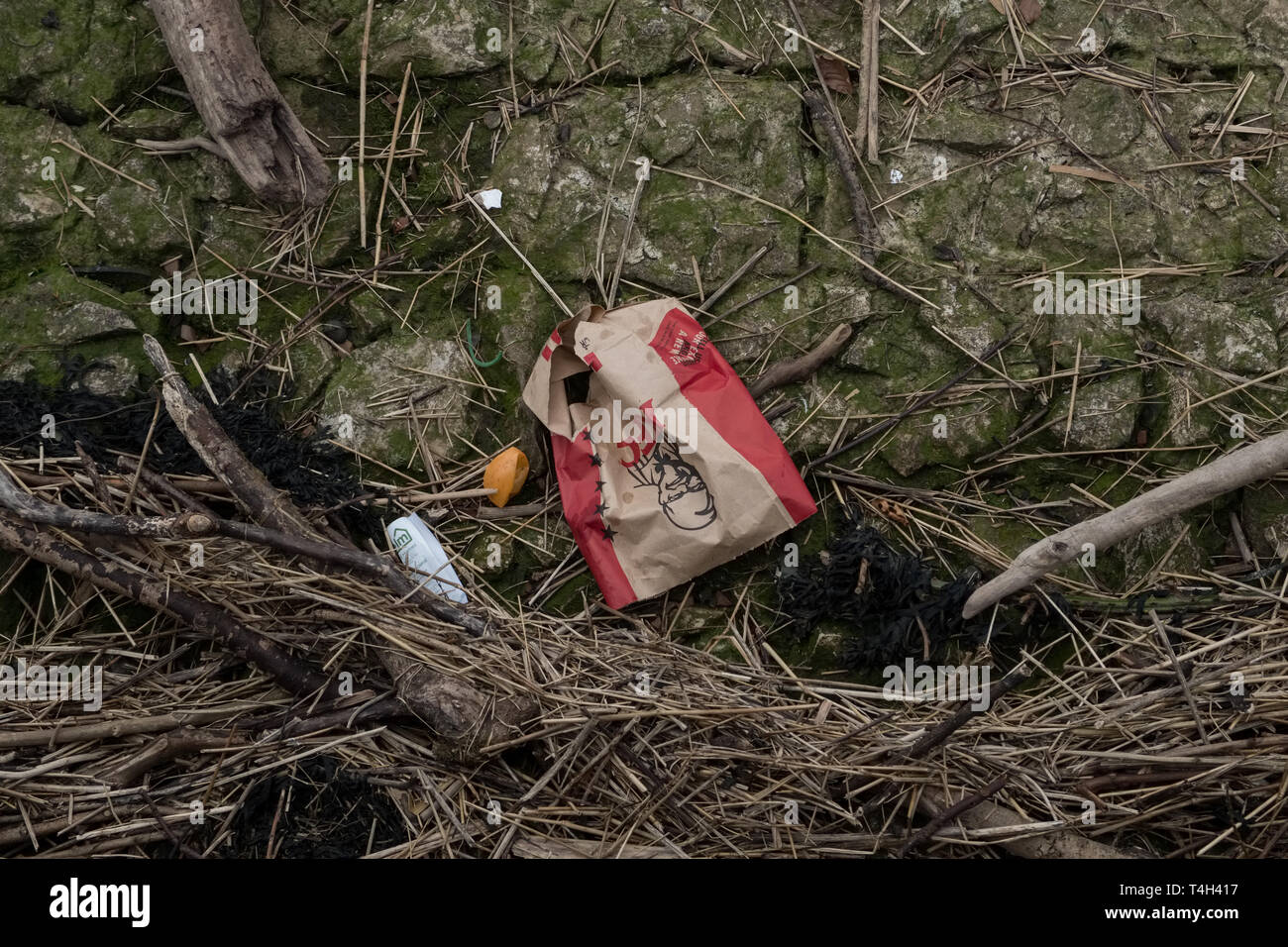 Irvine, Schottland, Großbritannien - 14 April, 2019: Abfall entsorgt am Strand mit Kunststoff- und papierbeutel von KFC sichtbar im Bild. Stockfoto