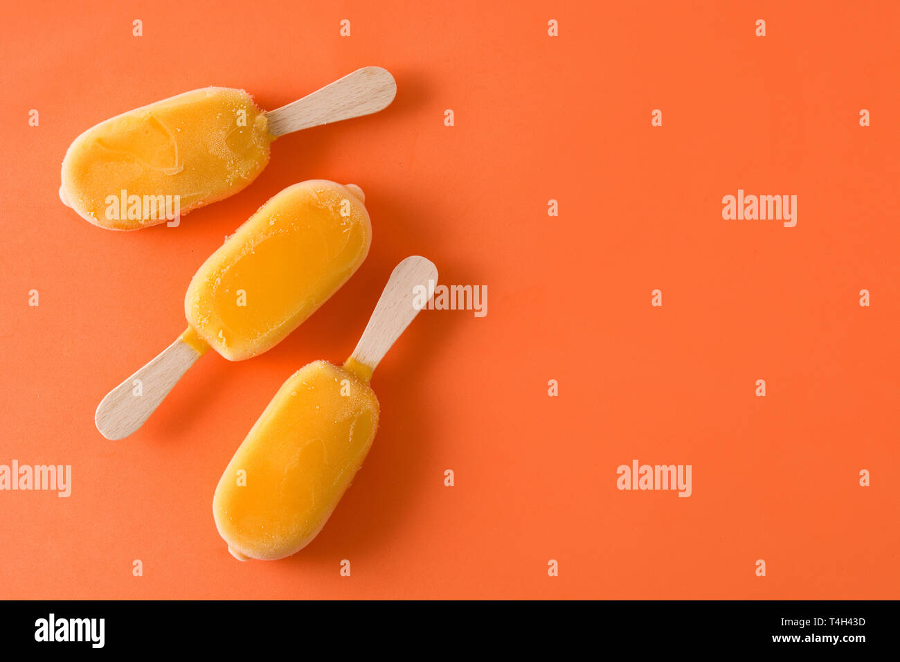 Orange Eis am Stiel Muster auf orangem Hintergrund. Ansicht von oben. Copyspace Stockfoto