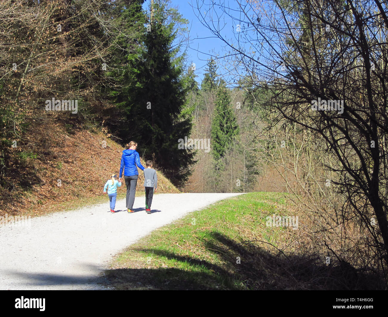 Mutter mit Sohn und Tochter wandern und Spaß und beeing glücklich zusammen und halten sich an den Händen. Familie Reise in einem Wald am Frühling. Stockfoto