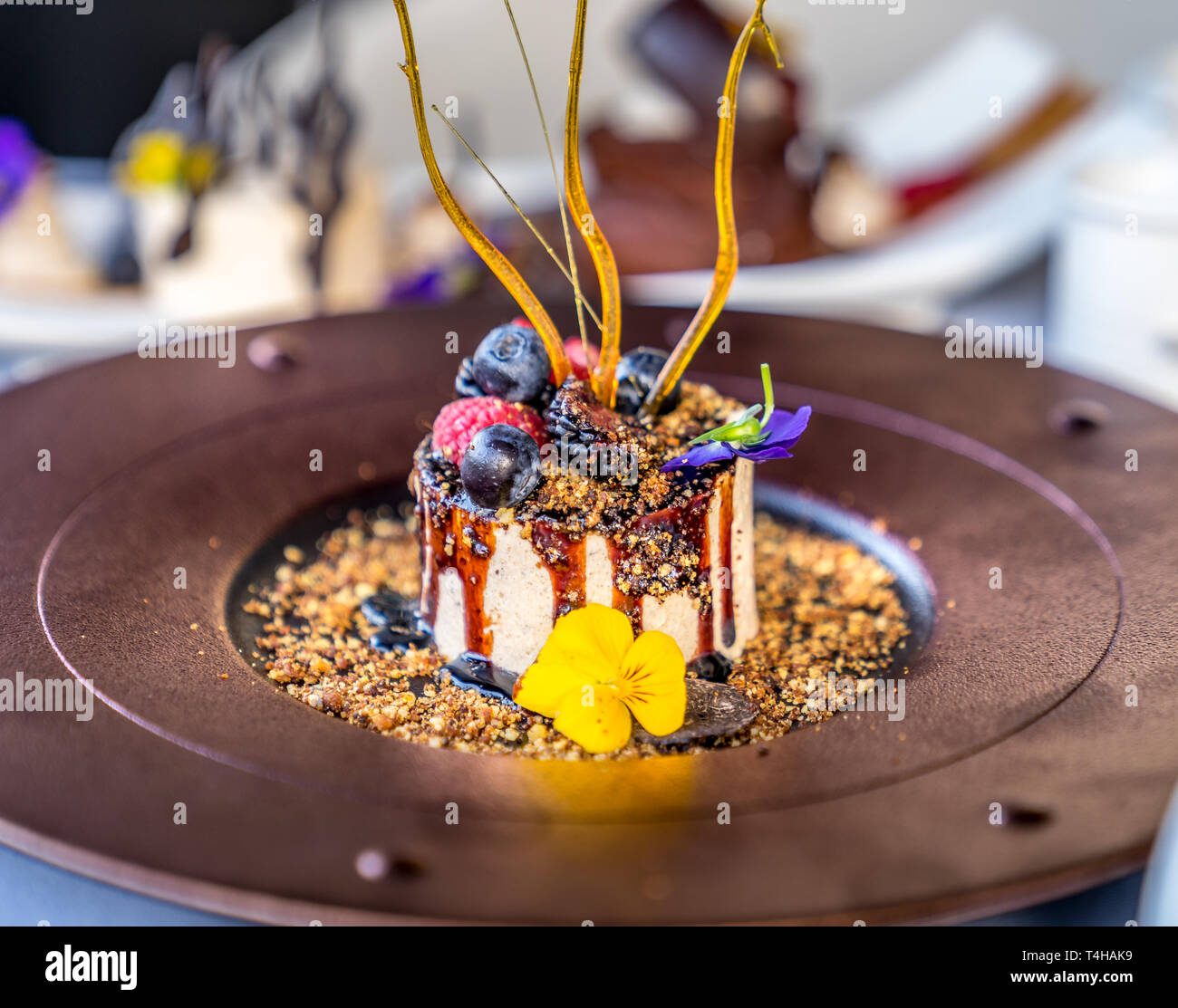 Schöne Vanilla Bean Eis, Crème Fraîche und Meersalz Karamell, mit Beeren und Blumen dekoriert Stockfoto