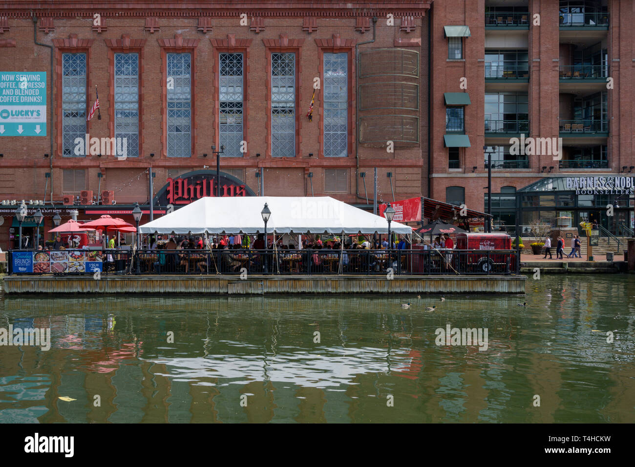 Baltimore, MD, USA --April 13, 2019-- Gönner Speisen im Freien unter einem Zelt an der Promenade von Inneren Hafen von Baltimore. Stockfoto