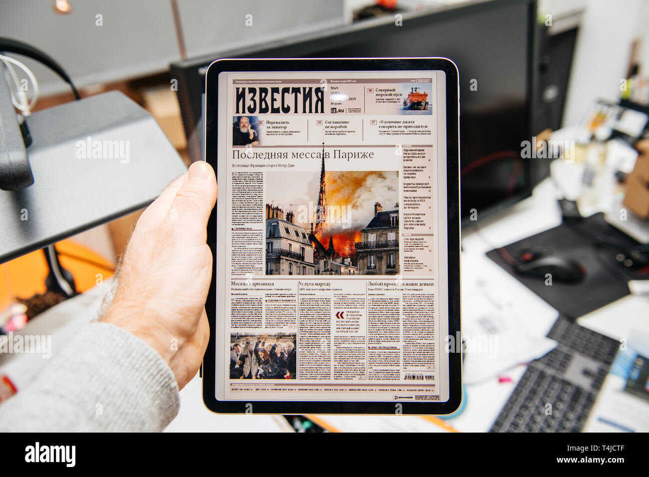 Paris, Frankreich, 15.April, 2019: der Mann, der das Lesen auf dem iPad pro Apple News Plus digitale Zeitung, die auf dem Deckel der Kathedrale Notre-Dame auf Feuer zu Schäden der berühmten Turm Iswestija zu reduzieren Stockfoto