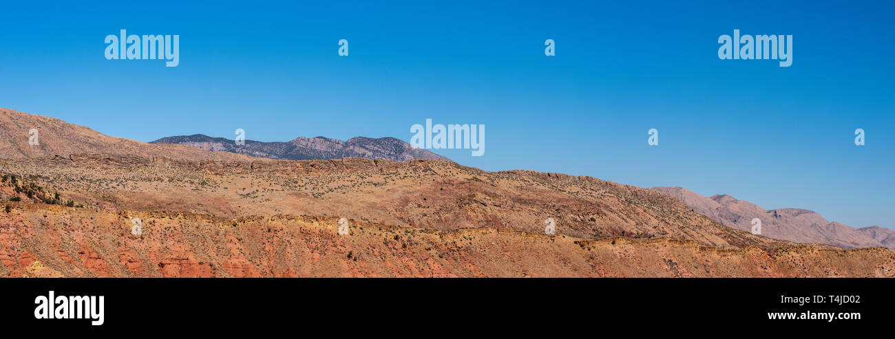 Panorama der farbenfrohen Orange und Gelb unfruchtbar felsigen Berghang unter einem blauen Himmel. Die wüstenberge. Stockfoto