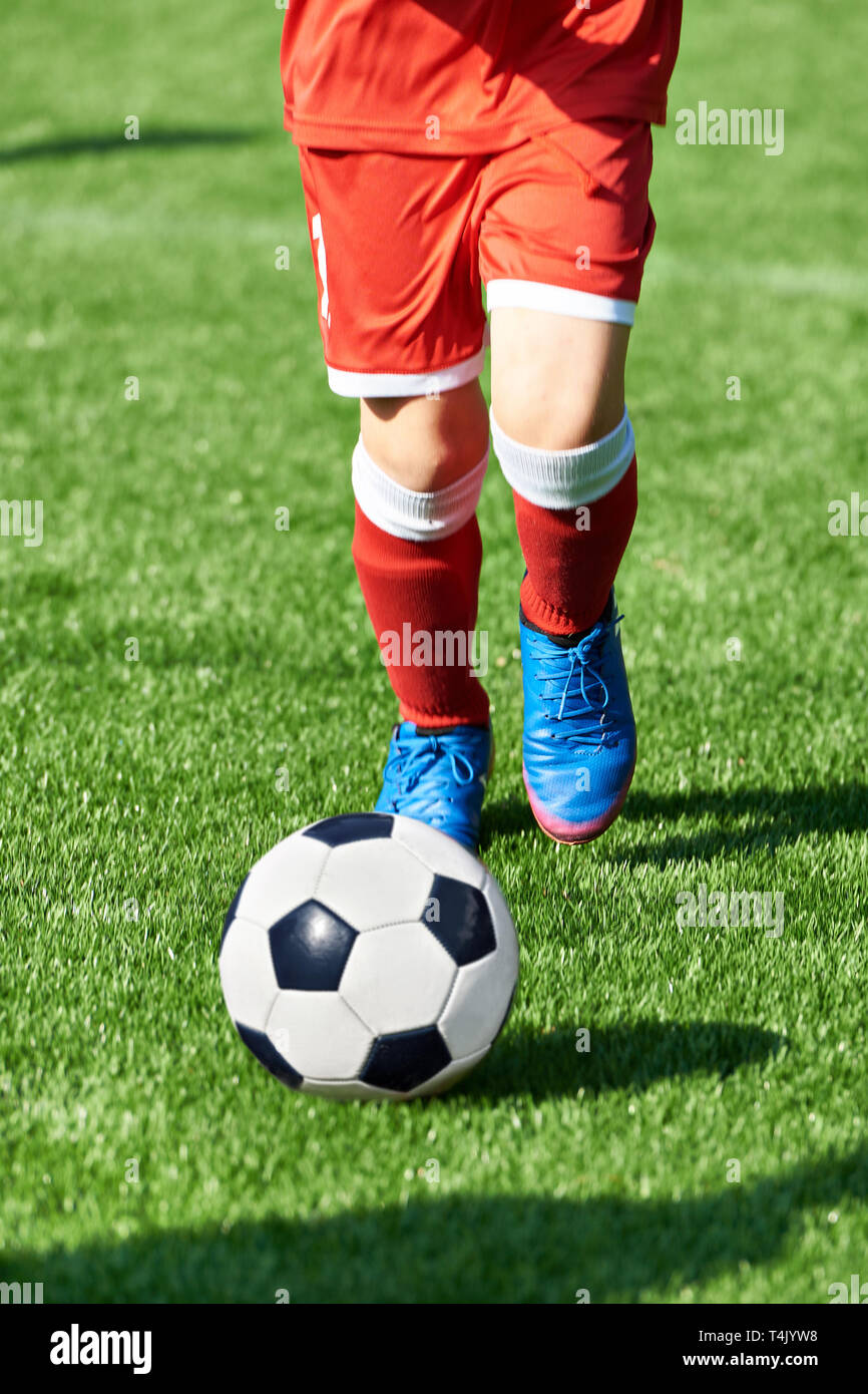 Junge Fußballspieler in rot Sport Uniform mit einem Ball auf dem Fußballplatz Stockfoto