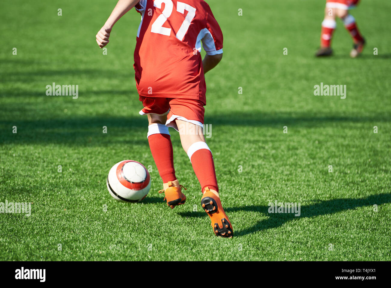 Junge Fußballspieler in rot Sport Uniform mit einem Ball auf dem Fußballplatz Stockfoto