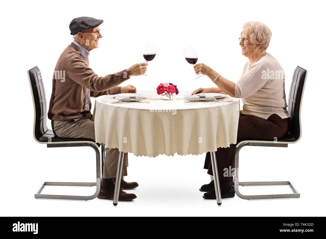 Älterer Mann und Frau, die Cheers mit Rotwein an einem Tisch auf weißem Hintergrund Stockfoto