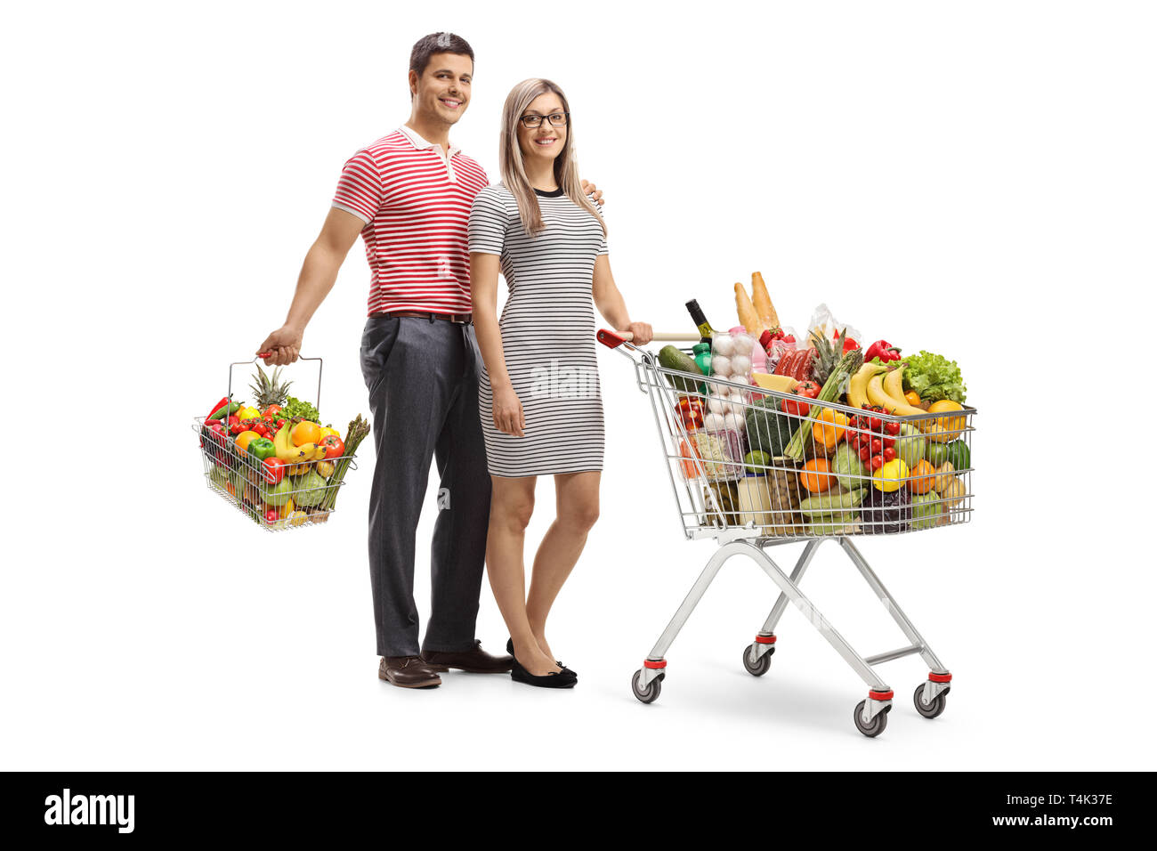 Junges Paar mit einem vollen Einkaufswagen und einem Warenkorb auf weißem Hintergrund Stockfoto
