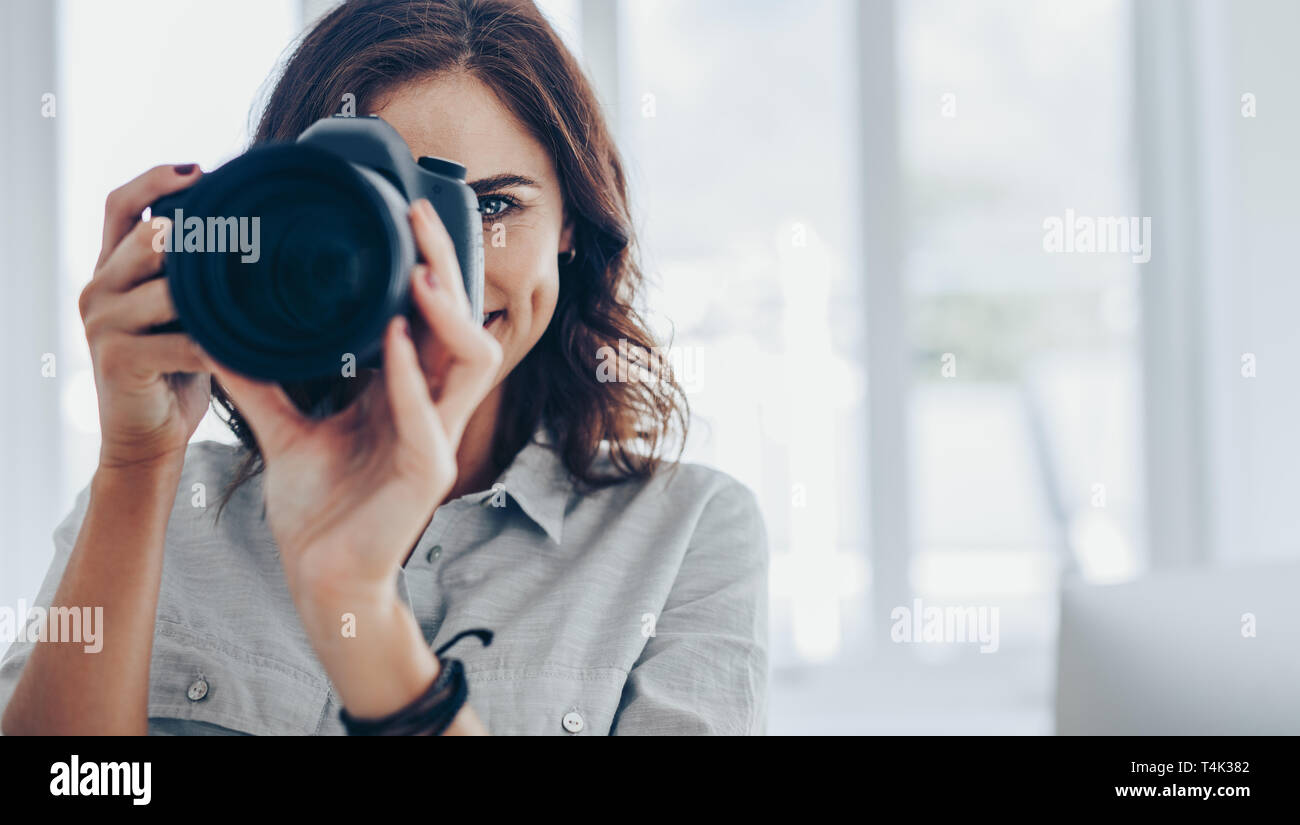 Frau Fotograf Bilder aufnehmen mit Ihrem professionelle DSLR-Kamera im Innenbereich. Weibliche unter Foto auf Digitalkamera. Stockfoto