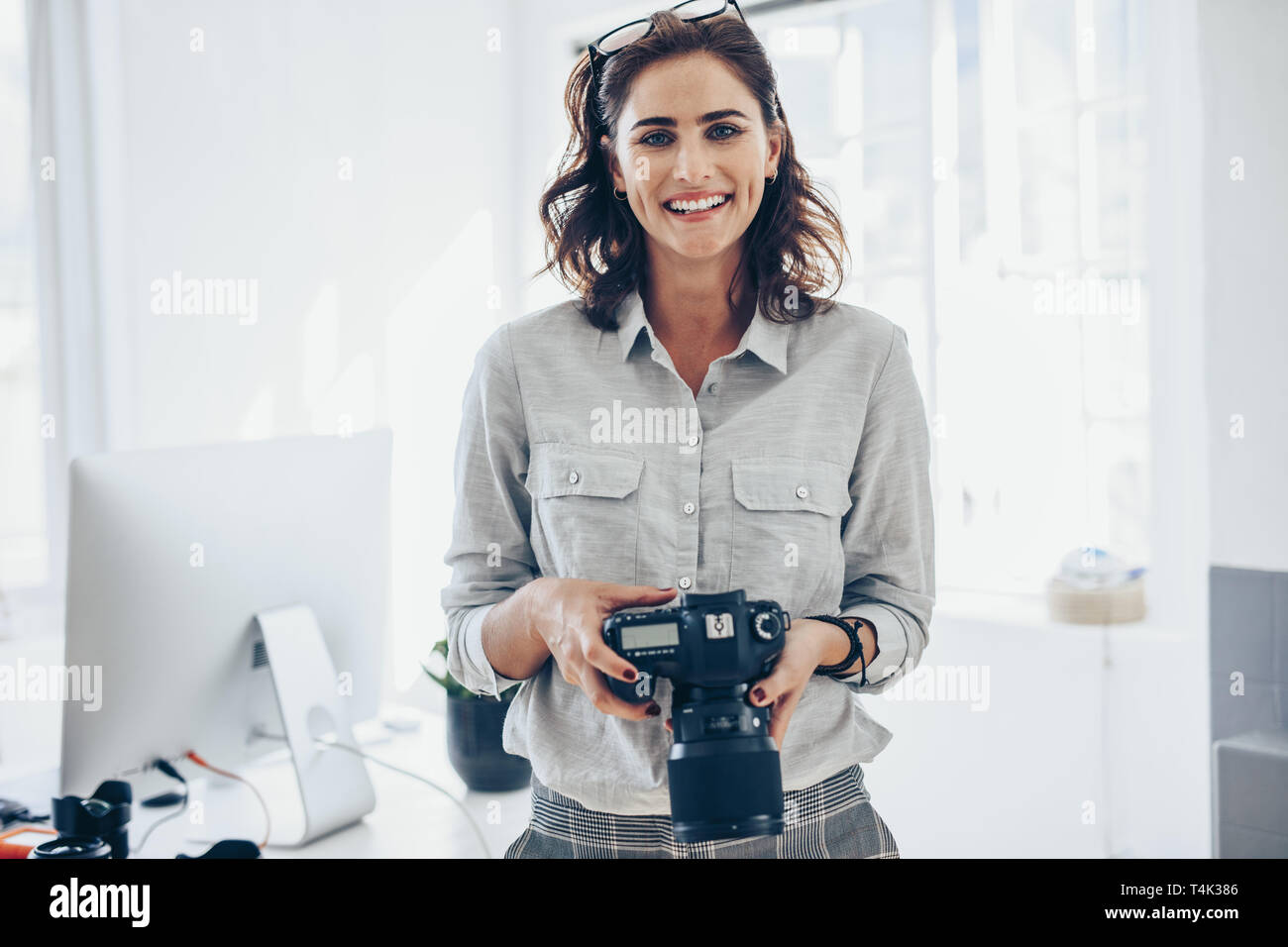 Attraktive junge Frau, die Fotografin mit Ihrer professionellen Kamera. Fotografin mit Digitalkamera im Amt. Stockfoto