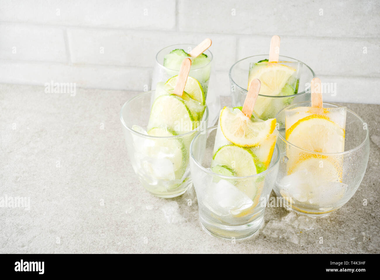 Gesunde Ernährung im Sommer Nachtisch, Vegan trendy Eis. Süß und Sauer infundiert Wasser Eis am Stiel mit Gurke, Kalk und Zitronenscheiben, grauen Stein backgroun Stockfoto