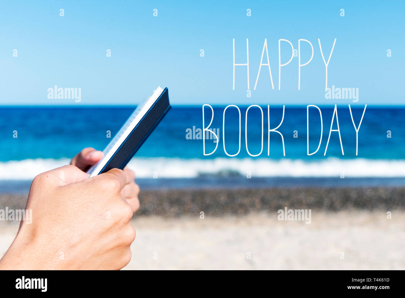 Nahaufnahme eines jungen kaukasischen Mann mit einem Buch am Strand, und der Text happy Buch Tag Stockfoto