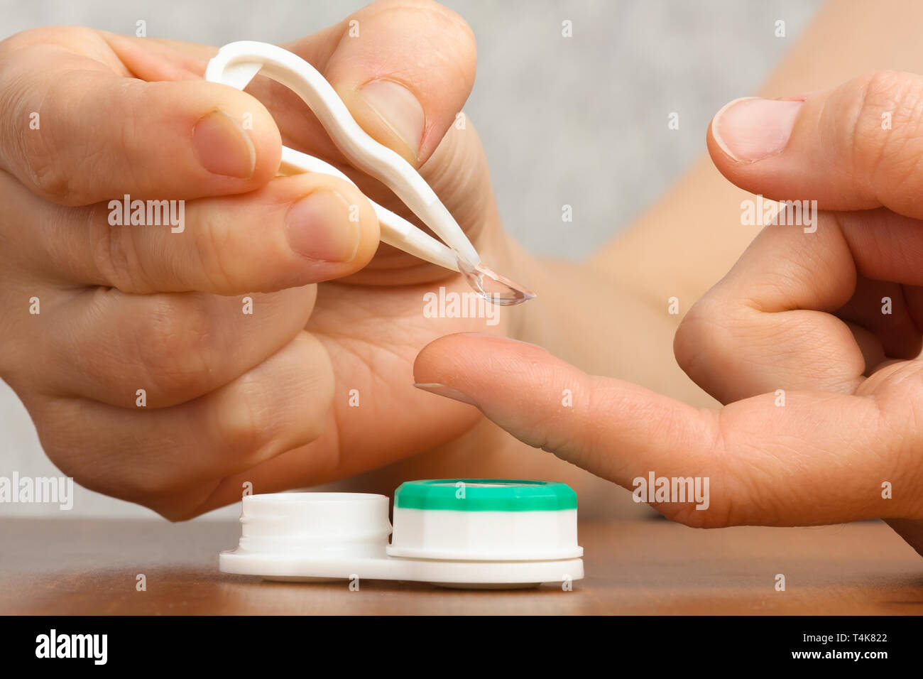 Hände mit Kontaktlinsen, Pinzette und Behälter Stockfoto