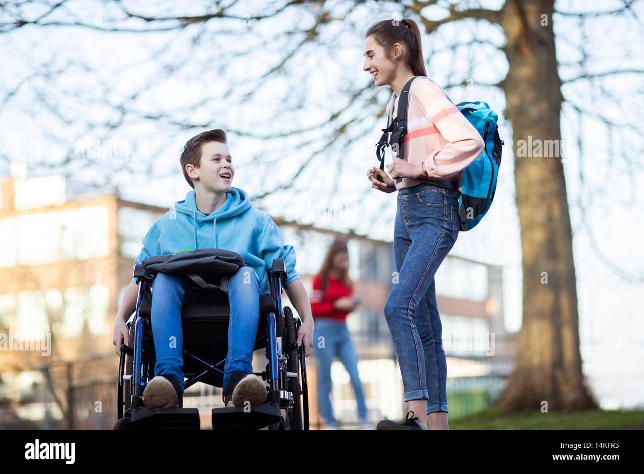 Teenager im Rollstuhl im Gespräch mit Freundin, wie sie High School verlassen Stockfoto
