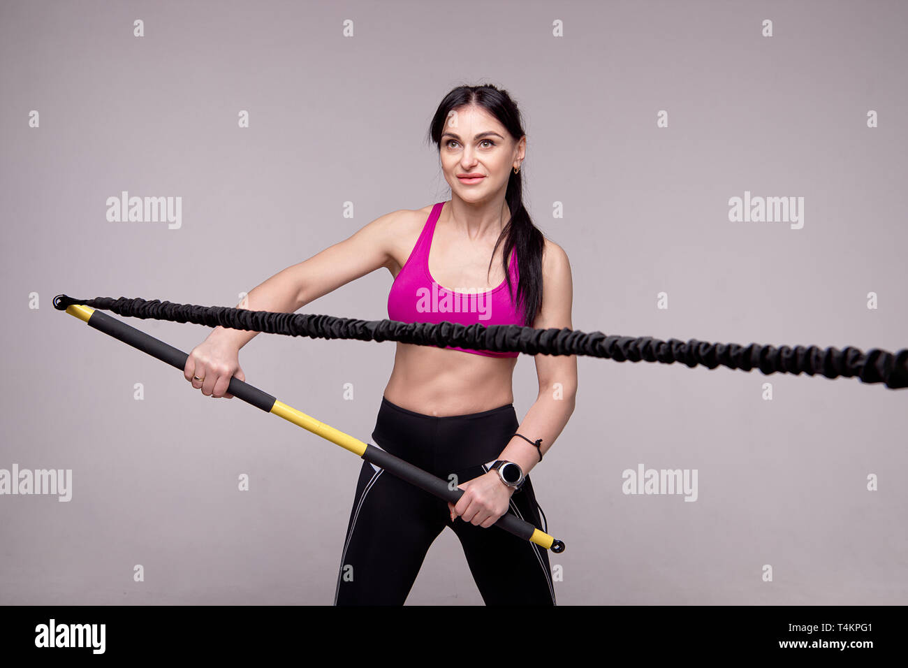 Sportliche Mädchen in Lila und Schwarz Sport leggings Züge mit einem Trainer Rip in der Turnhalle. Stockfoto