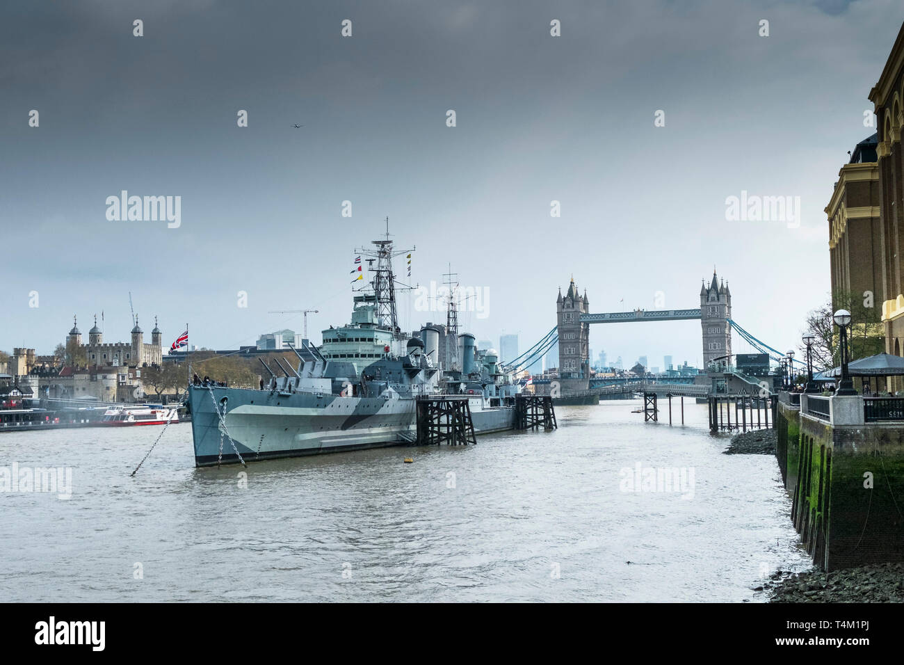 Die touristische Attraktion der HMS Belfast günstig auf der Themse in London mit dem Tower of London und die Tower Bridge im Hintergrund. Stockfoto