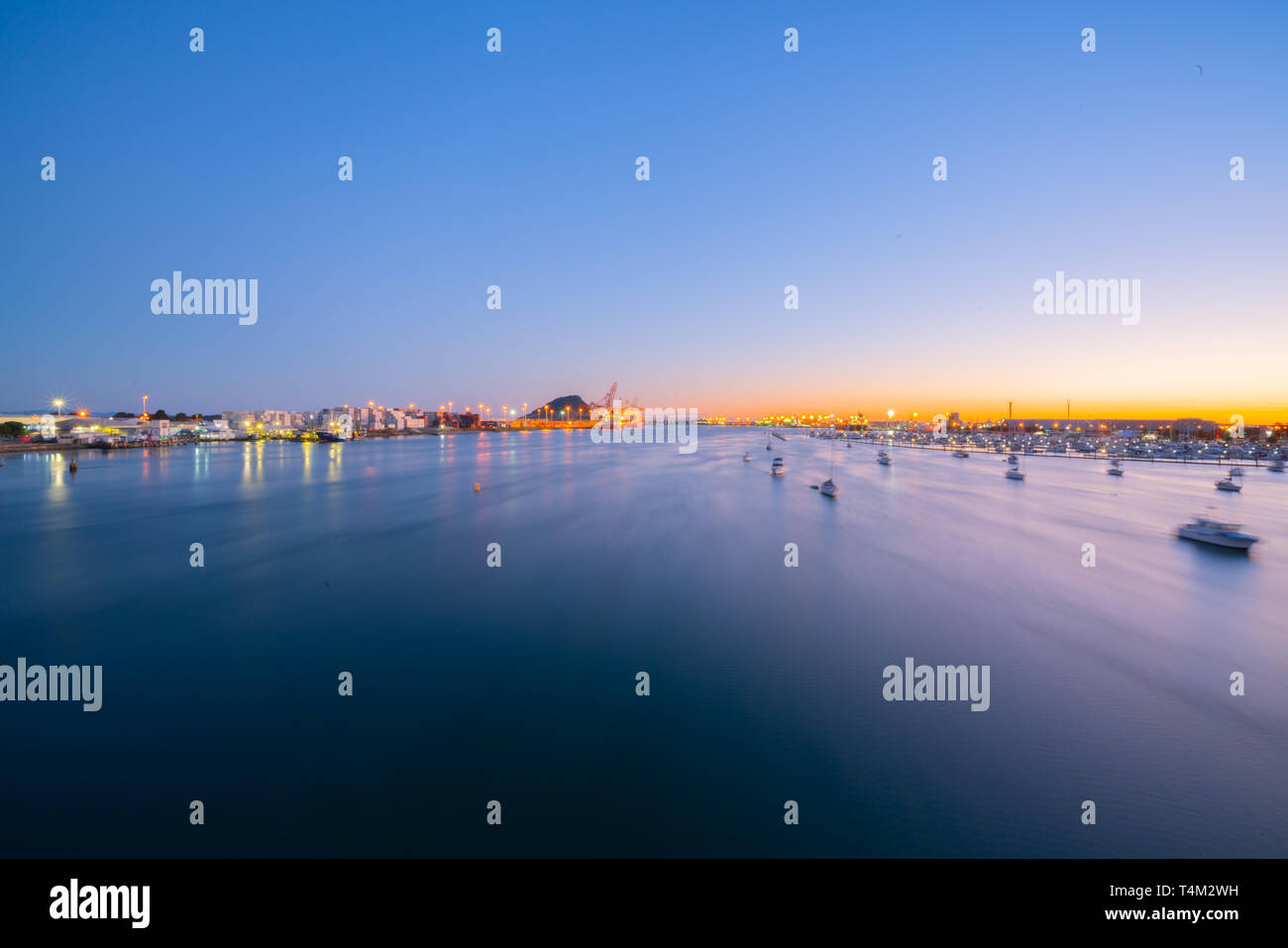 Defokussierten Lichter der Hafen von Tauranga Schiffe und Hafen in der Dämmerung mit goldenen Glanz der Sonne am Horizont. Stockfoto