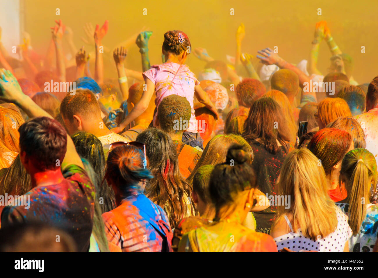 Eine Masse von jungen Menschen streut bunte Farbe auf den Holi Festival. Teens Spaß beim Festival der orientalischen Kultur. Stockfoto