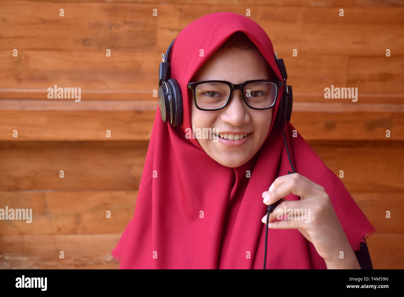 Asiatische muslimische Jugendliche, mit einem Lächeln über Handy zu Musik und selfies zu hören, Bilder von Ihnen nehmen Stockfoto