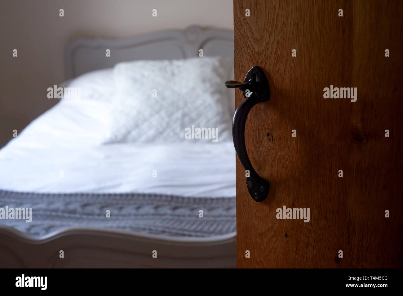 Ein ruhiges Schlafzimmer gesehen durch Offen-rustikale Holztür mit antiken Griff Stockfoto
