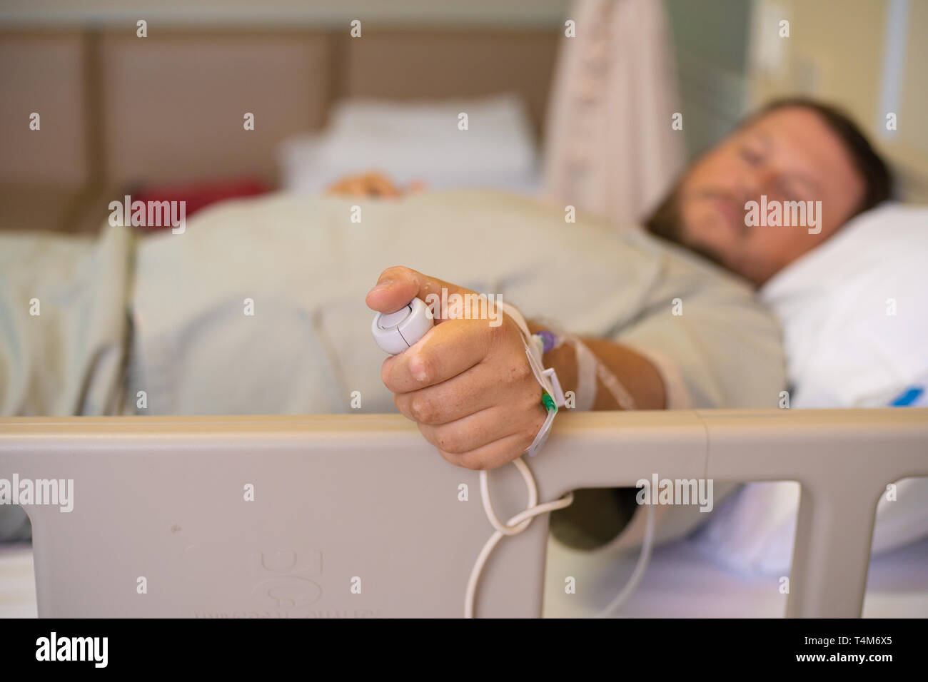 Mann in einem Krankenhaus als Krankenschwester. Eine Hand mit Not-Aus-Knopf im Krankenhaus Zimmer. Not-Aus-Taster für Patienten im Krankenhaus Stockfoto