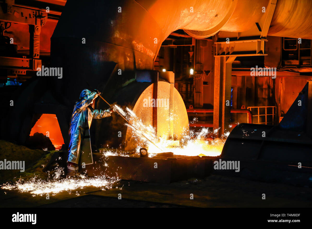 Duisburg, Ruhrgebiet, Nordrhein-Westfalen, Deutschland - ThyssenKrupp Stahl, ein Stahlarbeiter in einem Schutzanzug ist ein 1500 Grad heiß Roheisen Probe Stockfoto