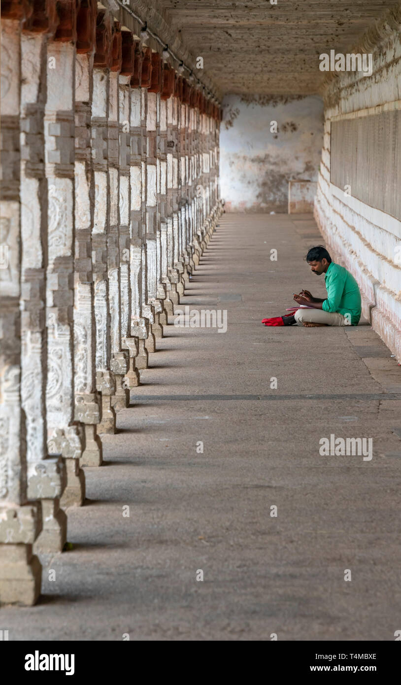 Vertikale Ansicht von einen Mann auf dem Boden an der Thillai Nataraja Tempel in Chidambaram, Indien sitzen. Stockfoto