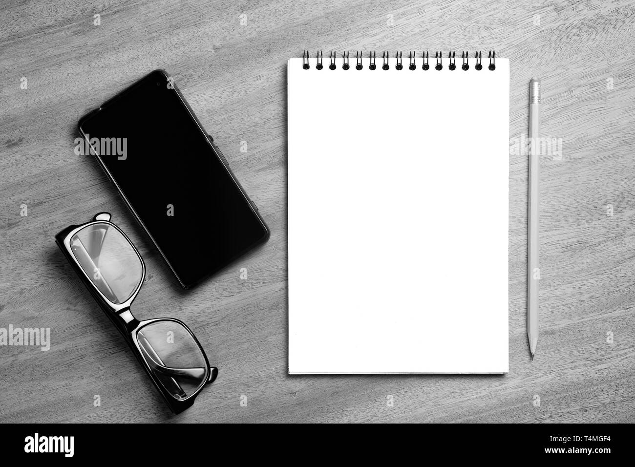 Business Essentials. Blick von oben auf die Spirale leer Notebook und Smartphone auf Holz Schreibtisch Hintergrund Stockfoto