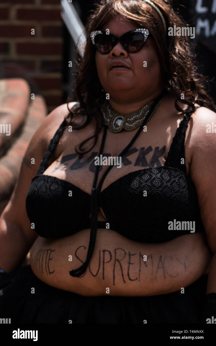 Schwarze Frau in Sonnenbrille mit Anti-rassismus-Slogan auf der Vorderseite des Körpers Stockfoto