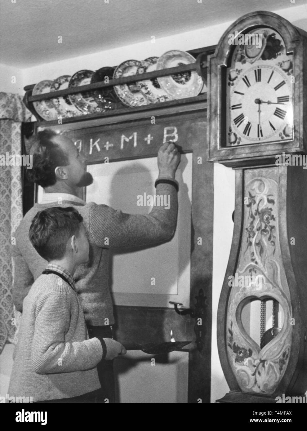 Am 3. Januar 1956, ein Vater und sein Sohn zeichnete die Initialen der Heiligen Drei Könige über eine Tür in einer Bauernstube in Deutschland. | Verwendung weltweit Stockfoto