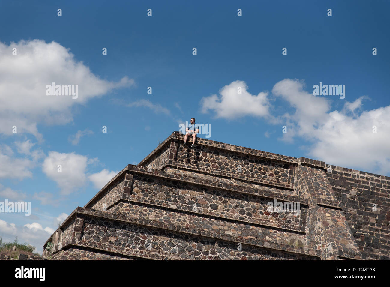 Ein einsamer Tourist sitzt an der Spitze der kleine Pyramiden von Teotihuacan, einer Mesoamerikanischen UNESCO-Weltkulturerbe seit 1987. Stockfoto