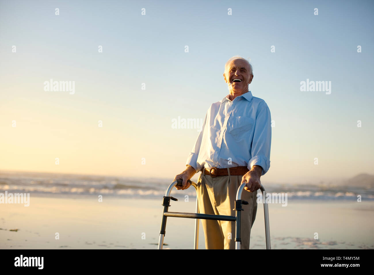 Portrait von ein älterer Mann stand auf einem Strand mit einer Gehhilfe. Stockfoto