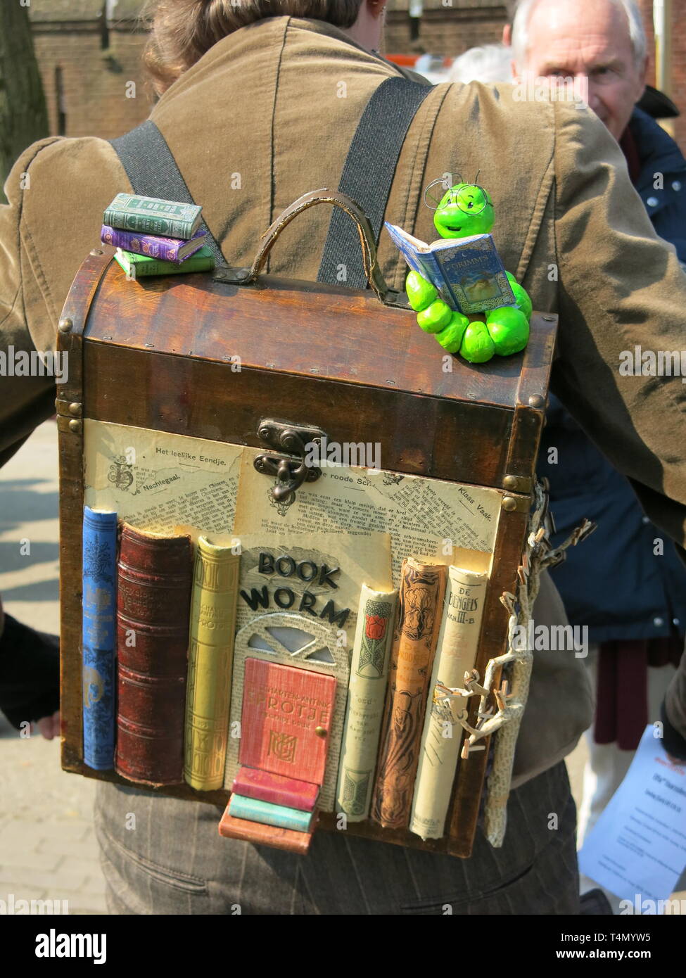 Festival - goer zu Elfia trägt einen Rucksack in der Form von einem Bücherregal, mit einem Book Worm; De Haar Schloss, April 2019 Stockfoto