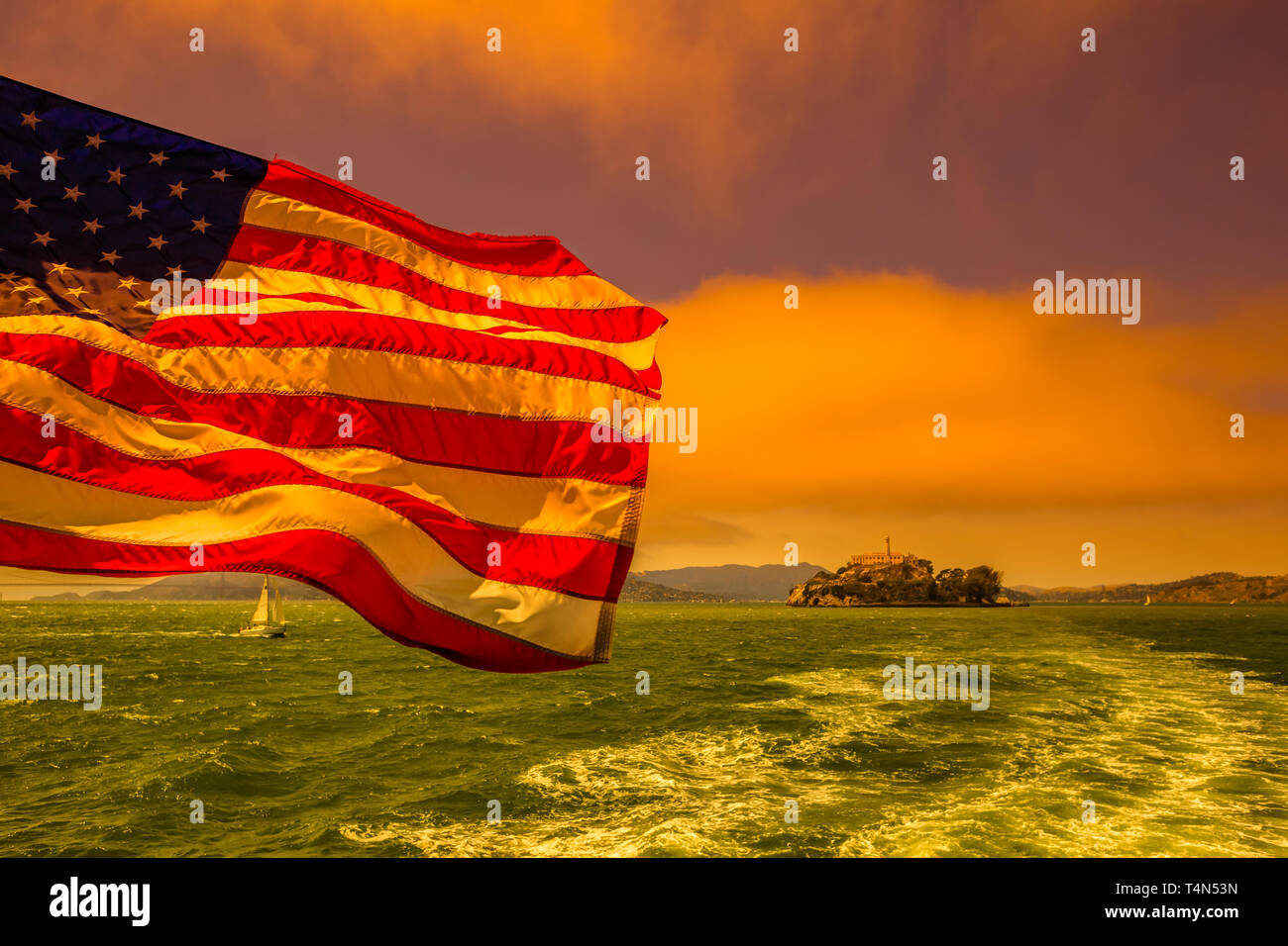 Fähre nach Alcatraz mit amerikanischer Flagge schwenken. Die Bucht von San Francisco Skyline, California, United States. Meerblick vom Boot zu Alcatraz bei Sonnenuntergang. Stockfoto