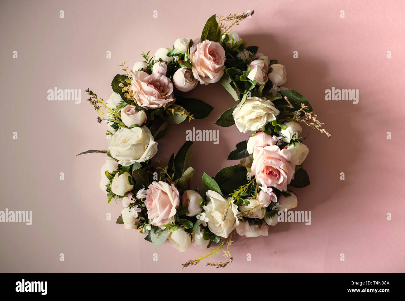 Kranz von rosa und weißen Rosen, grüne Blätter, Zusammensetzung rosa Blumen und grüne Blätter formen kreisförmige Rahmen auf rosa Hintergrund, Flach, Overhead Stockfoto
