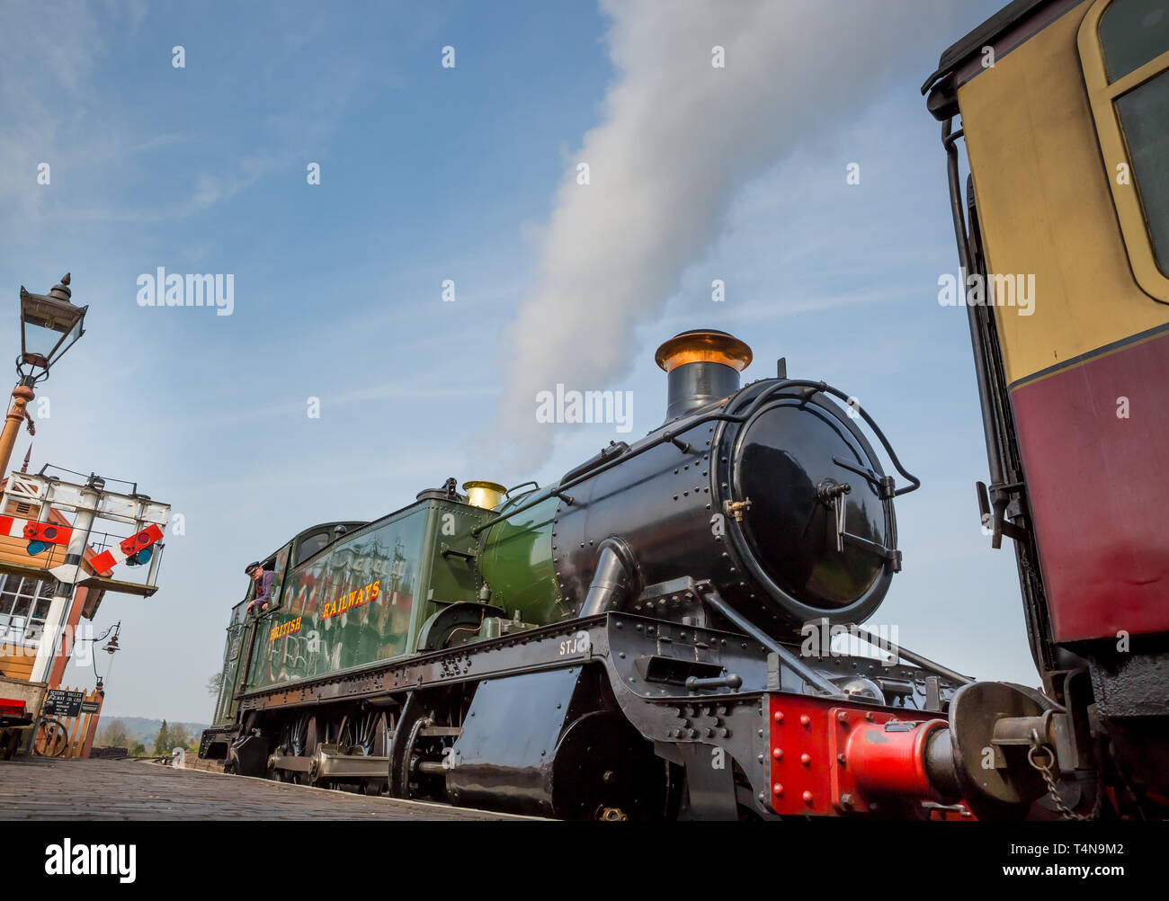 Niedriger Winkel, Vorderansicht Nahaufnahme der alten britischen Dampflok am Morgen Sonnenschein, während sie neben dem Bahnsteig am Bahnhof wartet. Stockfoto