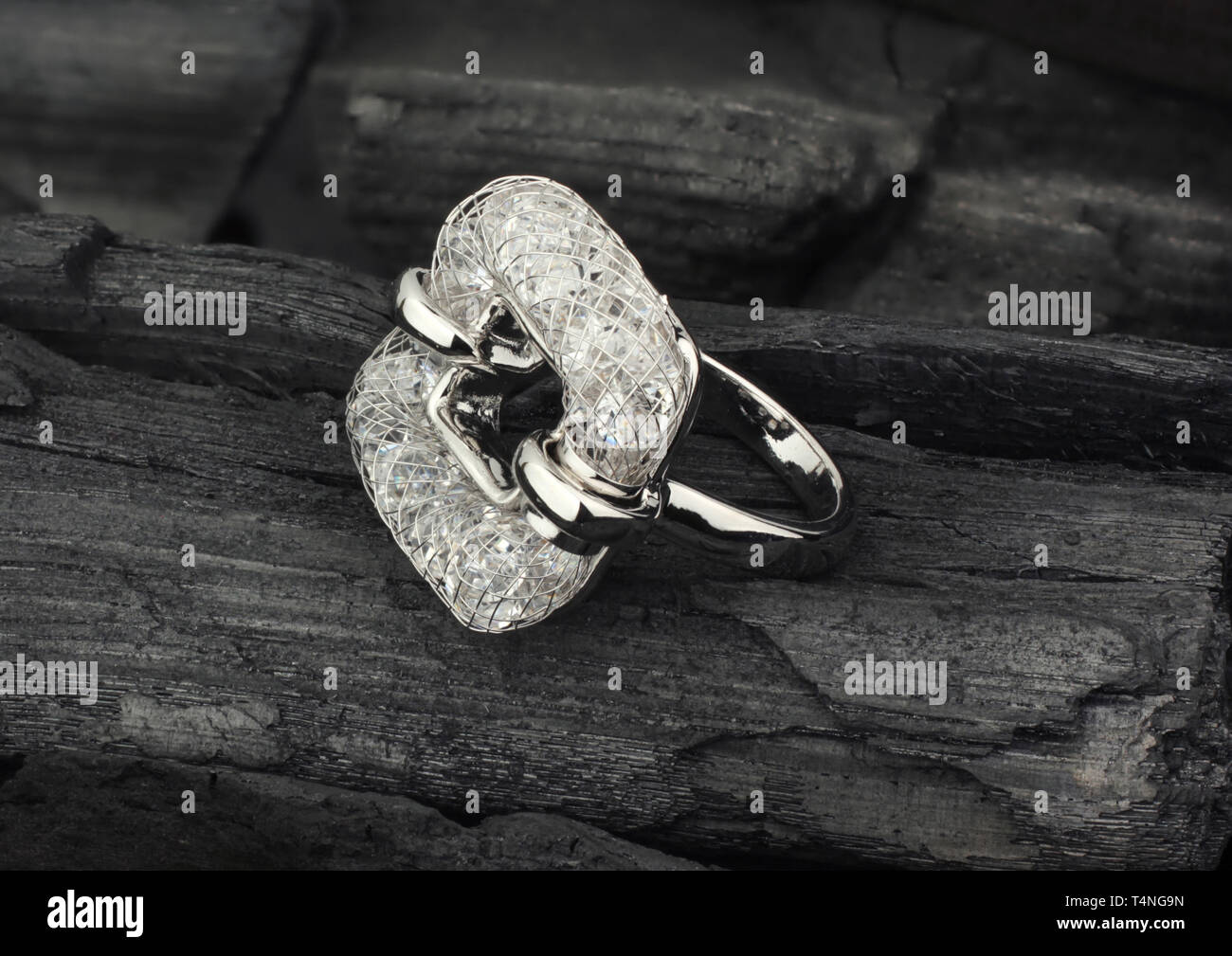 Goldene Schmuck Ring mit Diamanten, auf schwarzer Kohle als Hintergrund Stockfoto