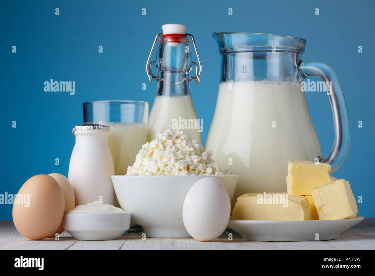 Molkereiprodukte, Milch, Quark, Eier, Joghurt, saure Sahne und Butter auf hölzernen Tisch Stockfoto