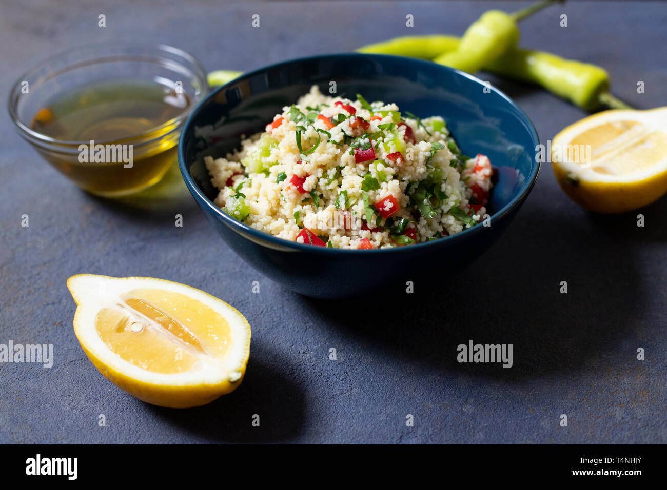 Tabbouleh Salat mit Couscous, Petersilie, Zitrone, Tomaten, Olivenöl. Levantinischen vegetarischen Salat. Libanesische und arabische Küche. Der dunkle Hintergrund. Nähe zu sehen. Stockfoto