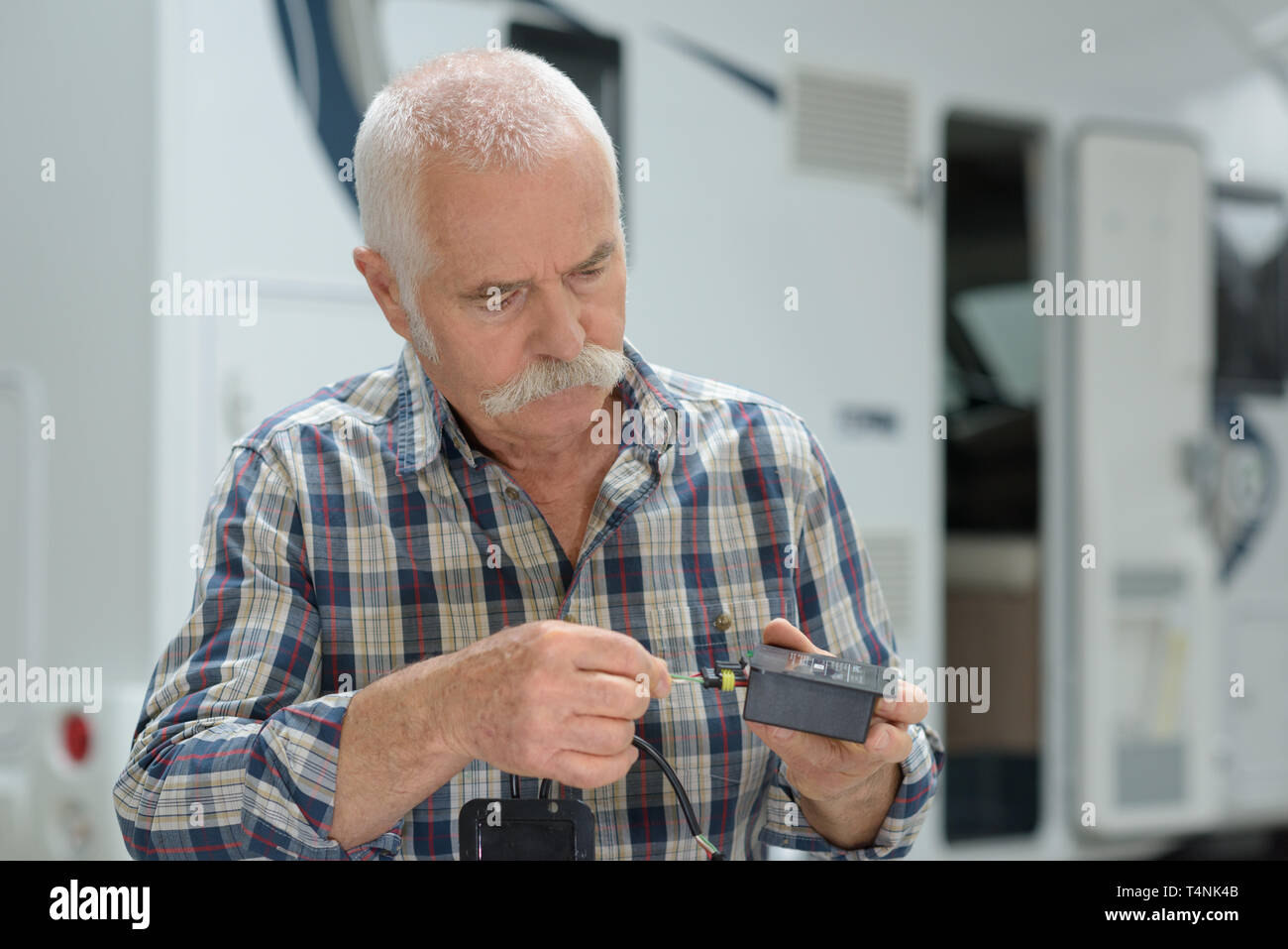 Älterer mann Prüfung elektrische Adapter außerhalb seiner Reisemobil Stockfoto