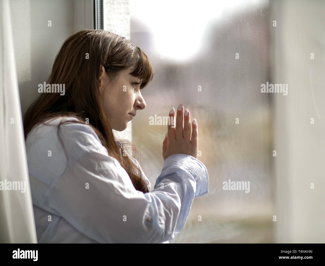 Traurig brünette Frau schaut aus dem Fenster Stockfotografie - Alamy