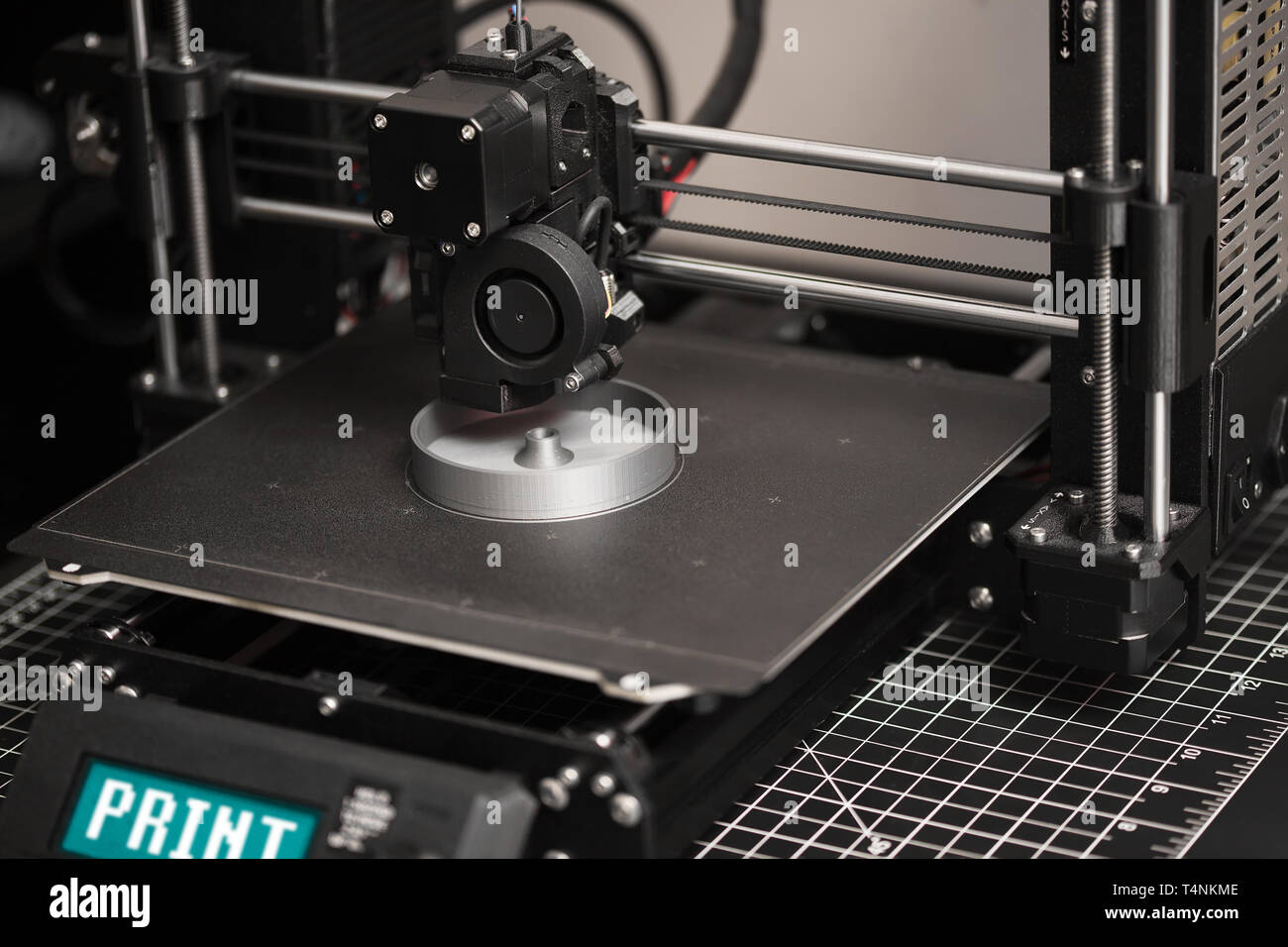 Ein 3D-Drucker in den Prozess der Druck eine digitale Datei oder einen Teil mit grauen Haar auf dem Metall heatbed. Stockfoto