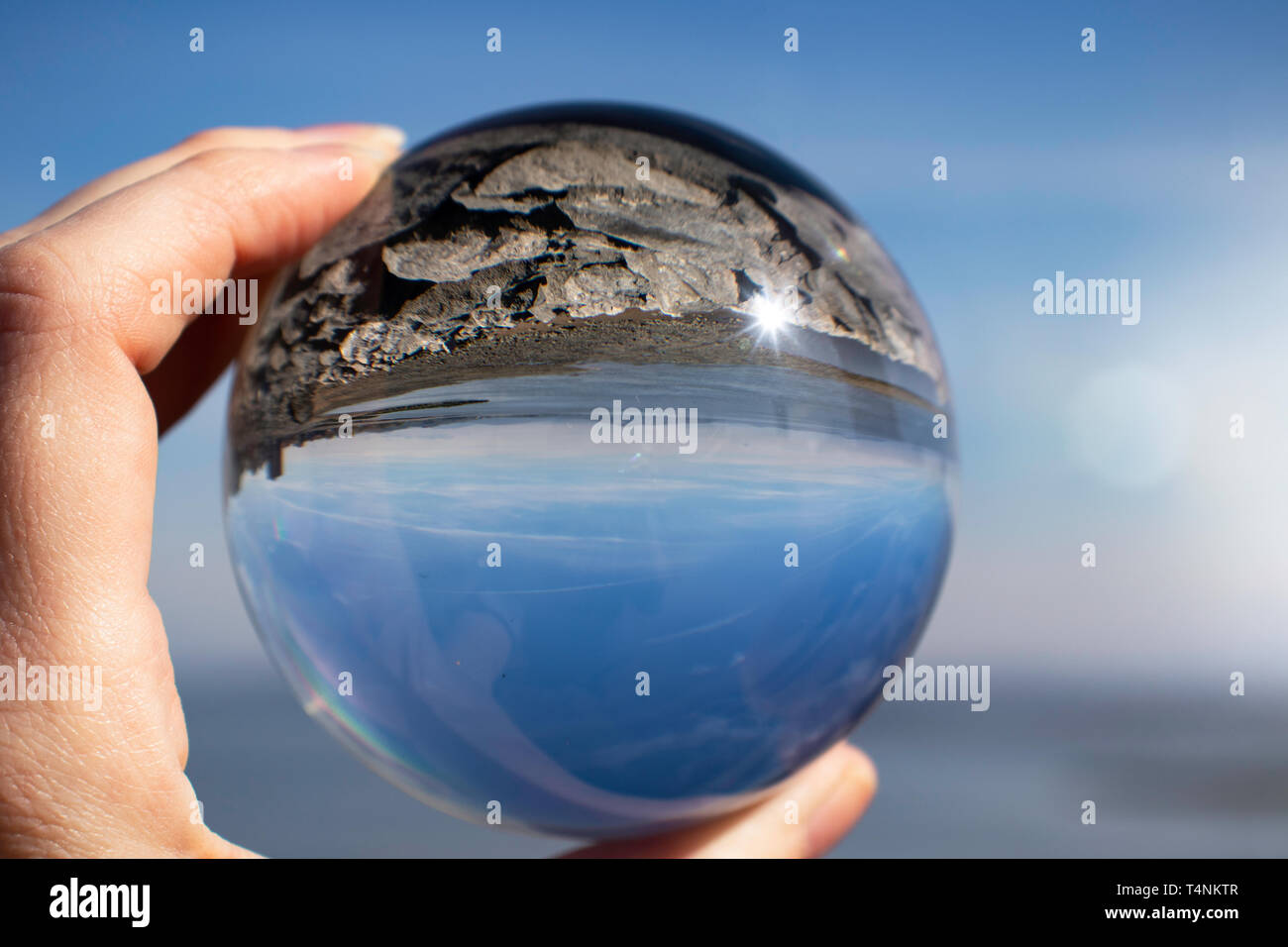 Morecambe Bay an einem klaren Frühlingstag, Lancashire, UK, als durch einen Kristall fotografie Kugel in eine weibliche Hand gesehen - Brechung Fotografie Stockfoto
