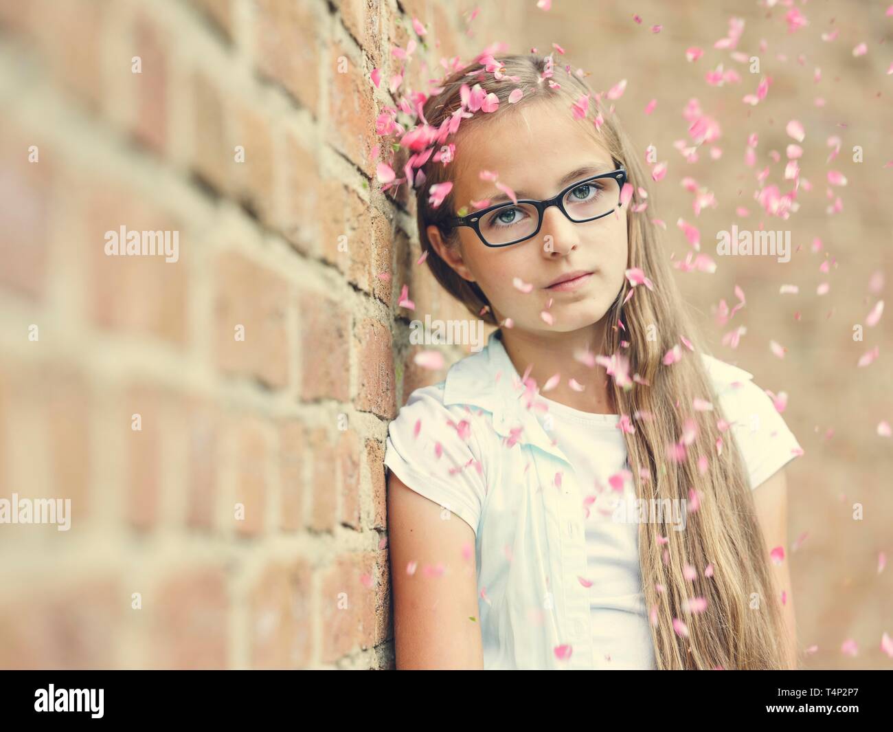 Mädchen mit Brille, Teenager, 12 Jahre, lehnt sich gegen eine Wand, Regen von Blumen, Porträt, Deutschland Stockfoto