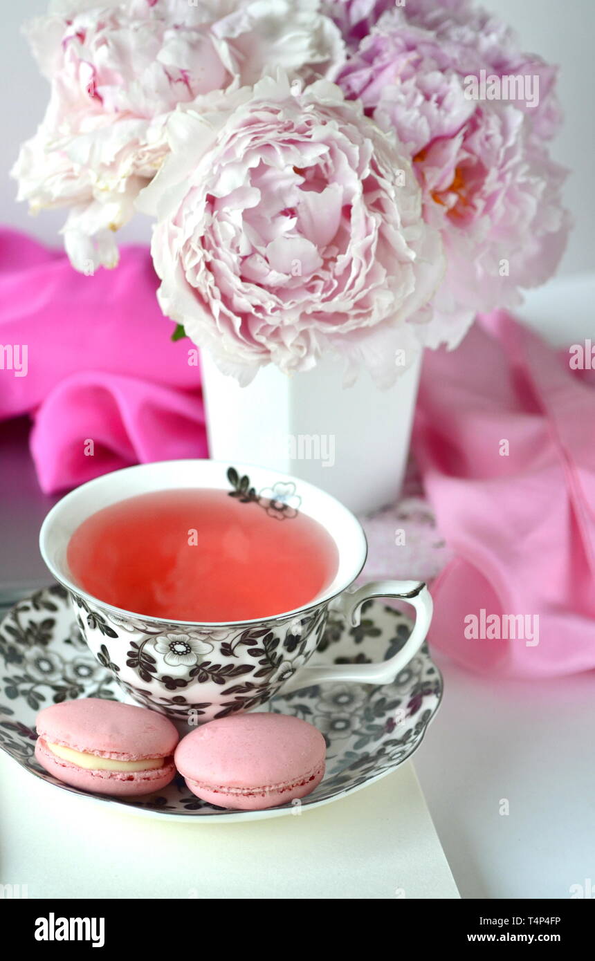 Elegant Gestalteten weiblichen Desktop - Entspannung, Lesen, kreatives Schreiben, Lernen und Journaling Konzept mit rosa Pfingstrosen, Obst Kaffee schickes Zubehör Stockfoto