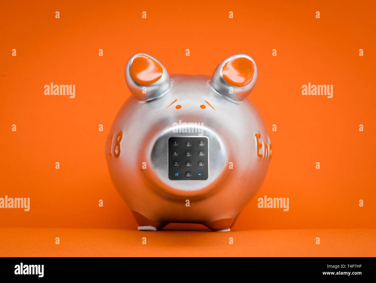 Metallic farbigen Sparschwein auf orangefarbenem Hintergrund mit einem Tastenfeld für die Eingabe der PIN am Schwein Nase. (Manipulierte) Stockfoto